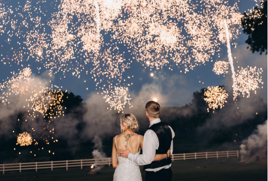 A couple celebrating their wedding beneath fireworks